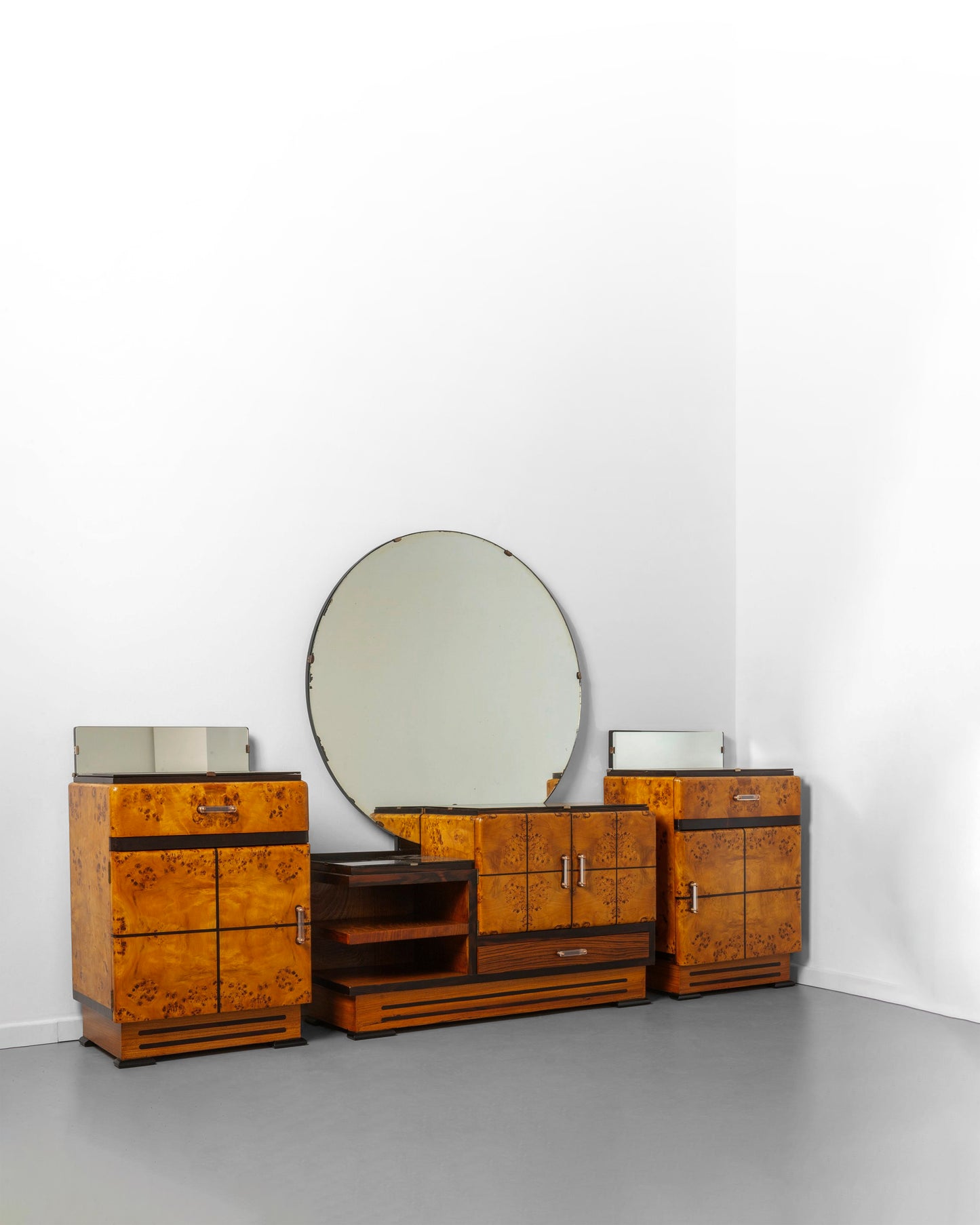 Art Deco bedroom set from the 1940s, crafted from elm wood with warm tones, including a dressing table with a round mirror and two matching nightstands, showcasing bold geometric lines and fine craftsmanship.