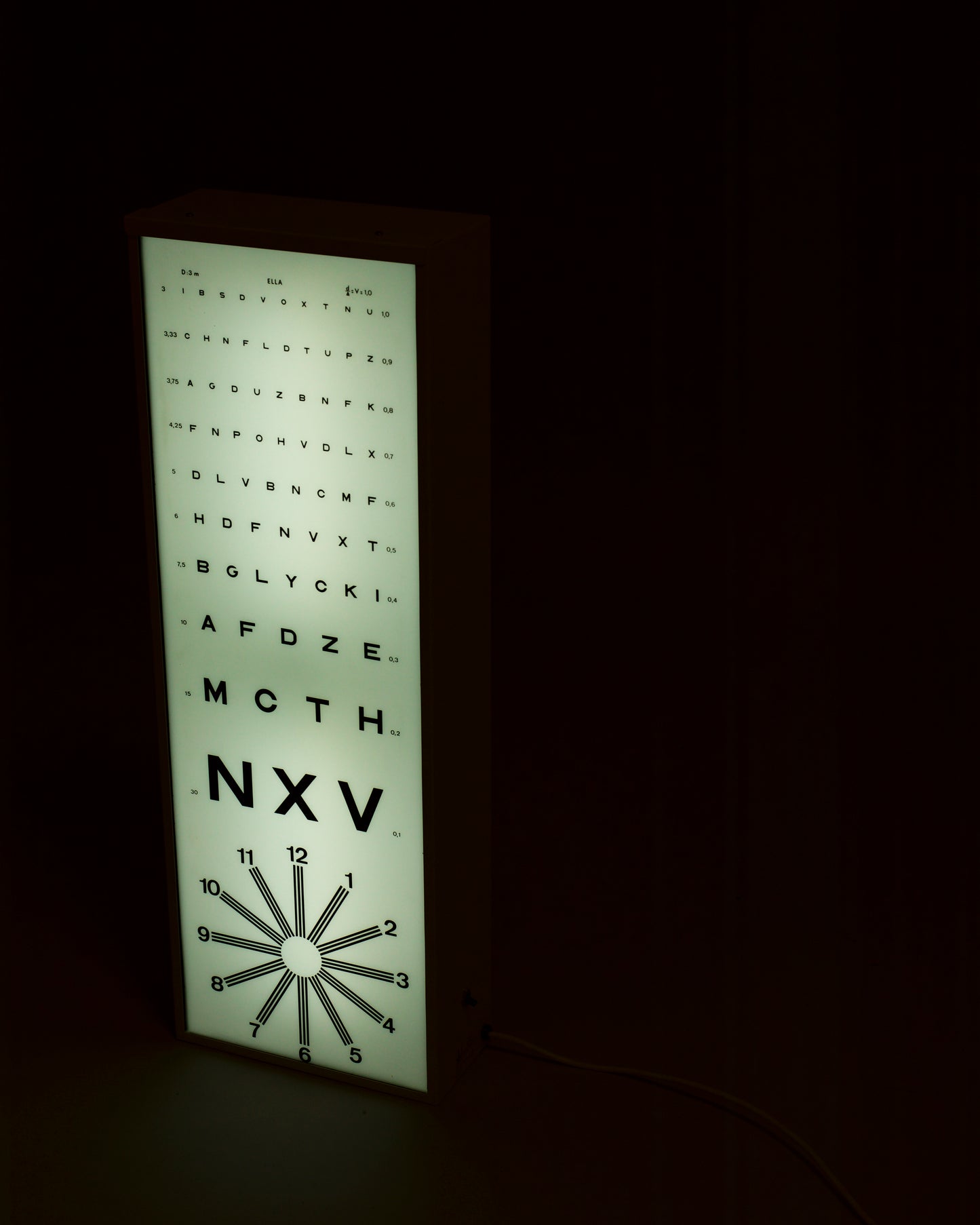 Luminous panel inspired by the Monoyer scale, featuring backlit visual acuity chart typography with a clean frame and soft glow, blending vintage aesthetics with modern graphic design.