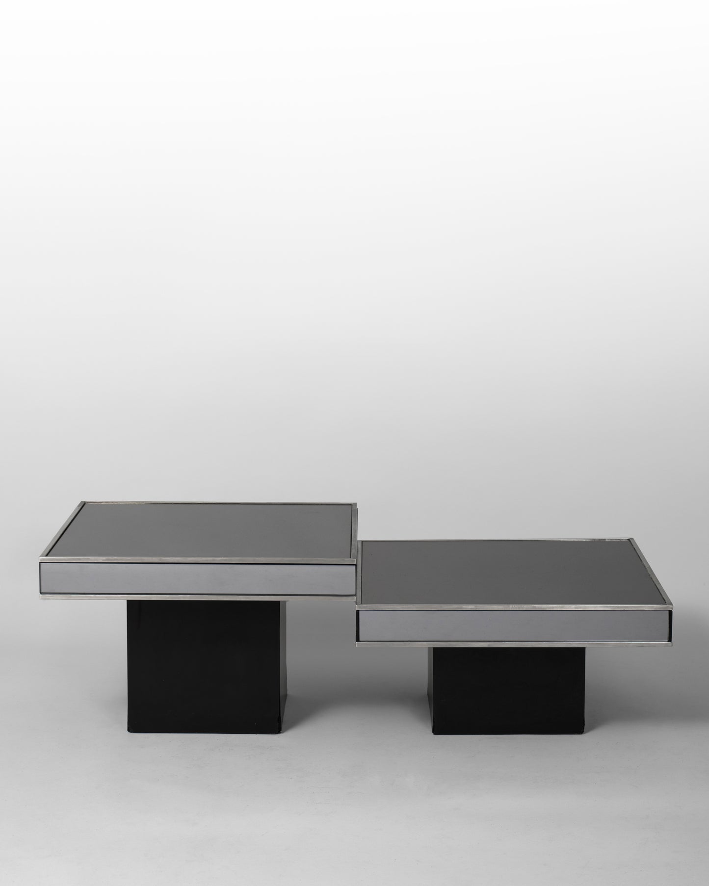 Pair of nesting tables designed by Willy Rizzo for Cidue in the 1970s, featuring chromed metal frames and black mirrored glass surfaces, blending Italian modernism with sculptural elegance.