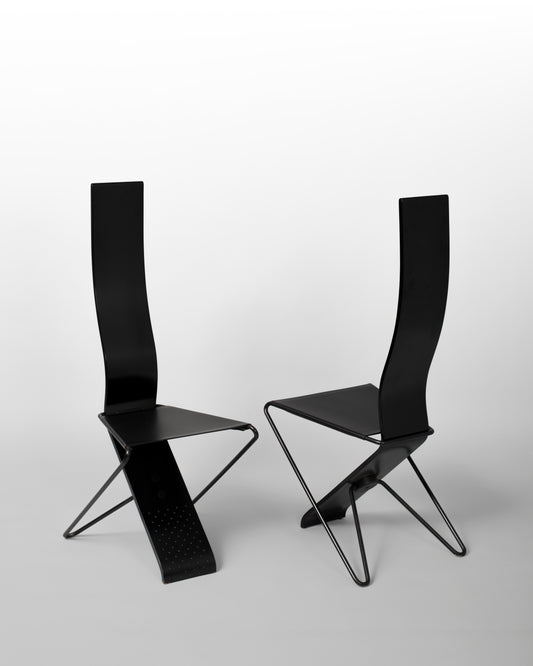 Pair of postmodern chairs designed by Pietro Arosio in the 1980s, featuring sleek black steel structures, perforated seats, and bold geometric forms, embodying avant-garde Italian design and industrial aesthetics.