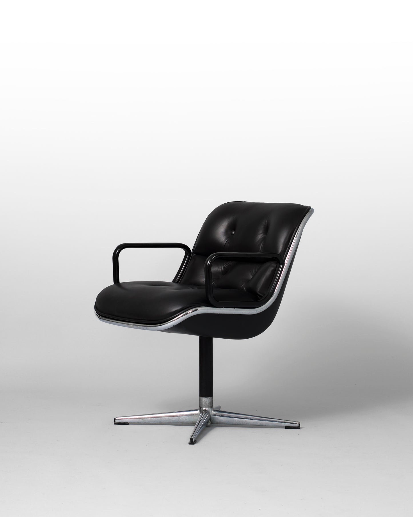 Stationary armchair designed by Charles Pollock for Knoll International in the 1960s, featuring a black leather seat, chrome star-shaped base, and mid-century modern design with geometric elegance.