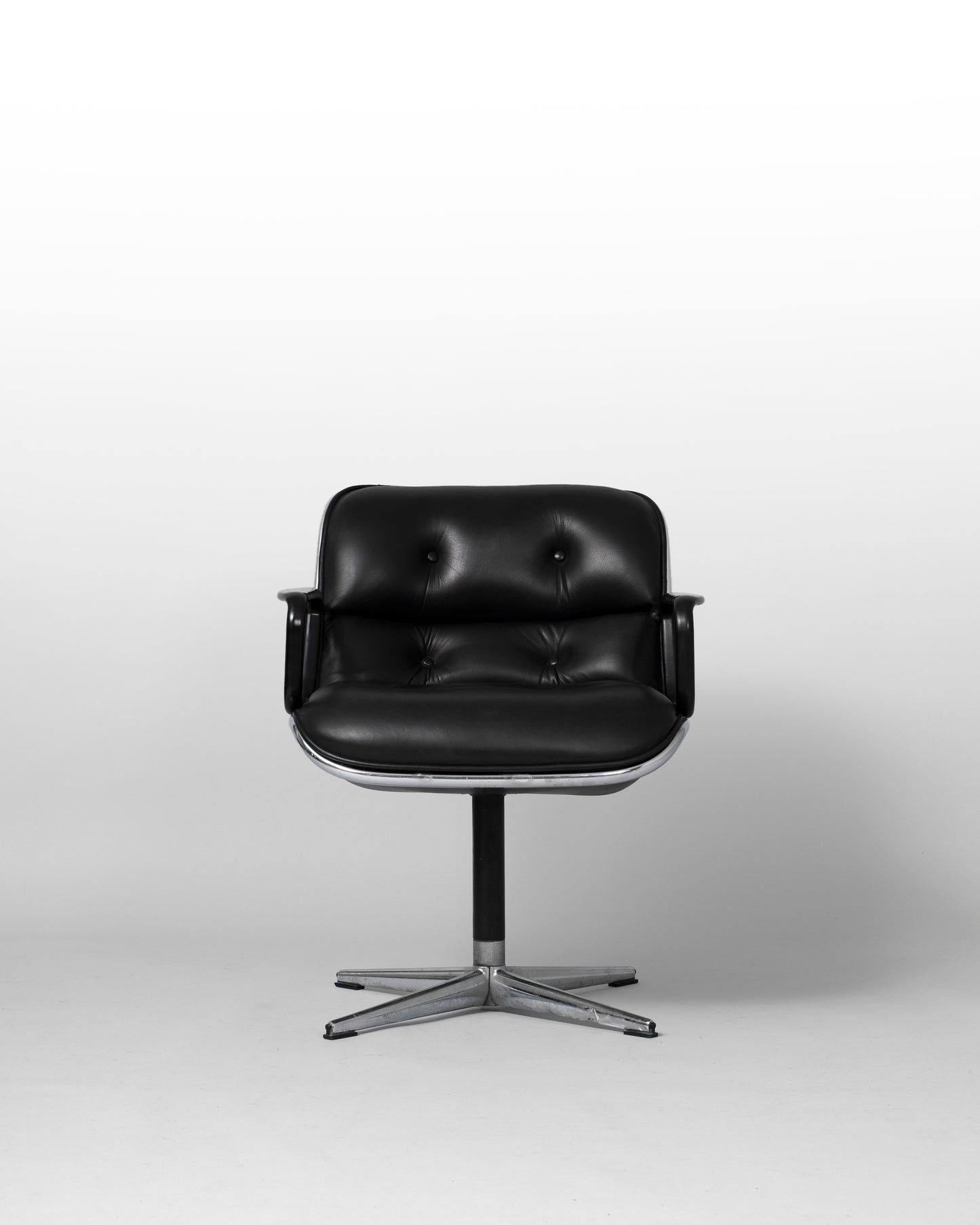 Stationary armchair designed by Charles Pollock for Knoll International in the 1960s, featuring a black leather seat, chrome star-shaped base, and mid-century modern design with geometric elegance.