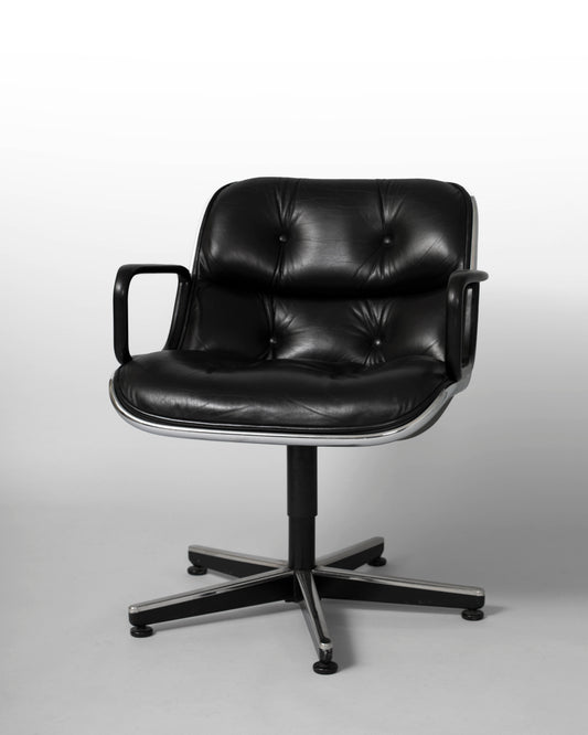 Swivel armchair designed by Charles Pollock for Knoll International in the 1960s, featuring a black leather seat, chrome star-shaped rotating base, and mid-century modern aesthetics, combining comfort with geometric elegance.